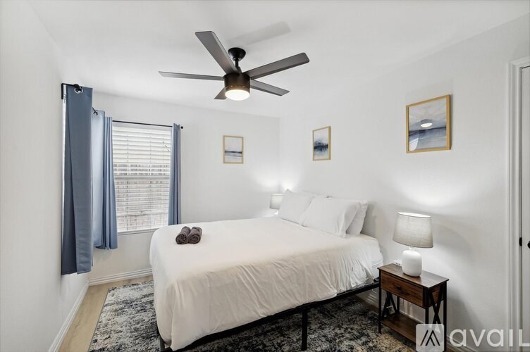 A bedroom with a bed, a ceiling fan, and a nightstand with a lamp.