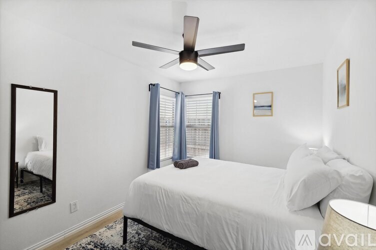 A bedroom with a bed, a ceiling fan, and a mirror.