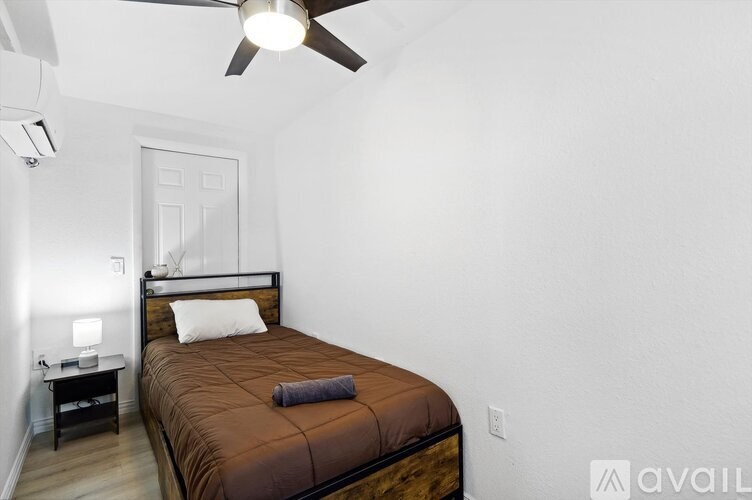 A bedroom with a bed, a nightstand, and a ceiling fan.
