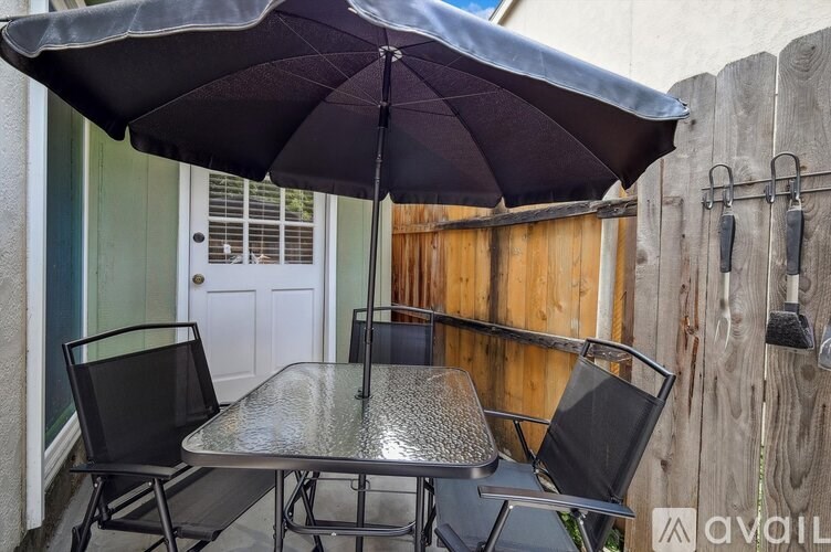 A patio table with chairs and an umbrella is set up on a wooden deck.