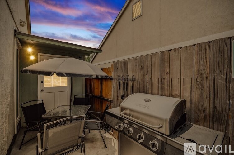 A grill and chairs are set up on a patio.