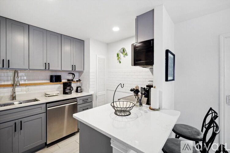 A modern kitchen with a white countertop and grey cabinets.