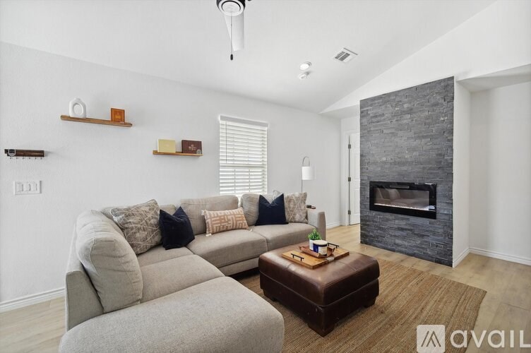 A living room with a grey couch, a coffee table, and a fireplace.