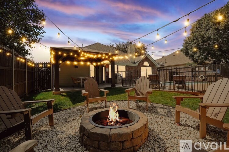 A backyard with a fire pit and chairs.