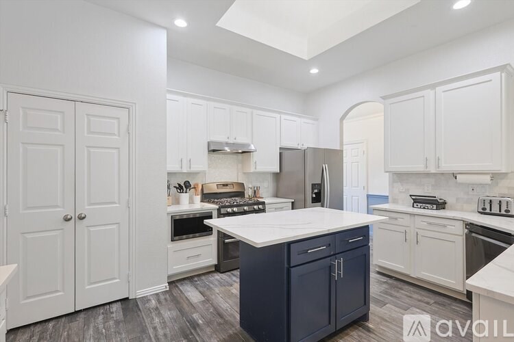 A kitchen with white cabinets and a dark island.