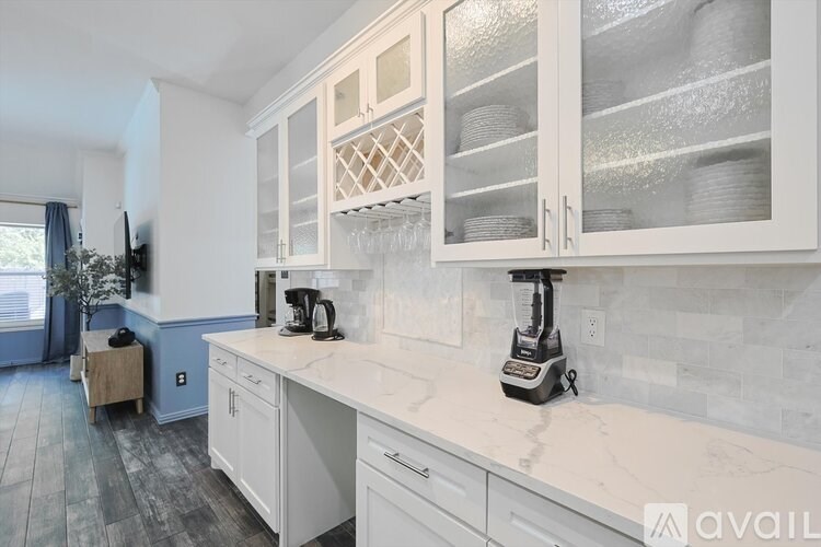 A kitchen with white cabinets and a marble countertop.