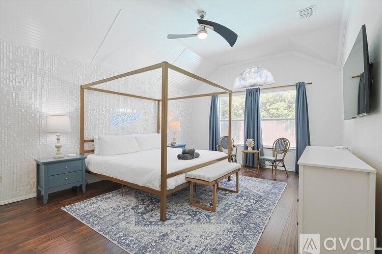A bedroom with a four poster bed, a bench, and a fan.