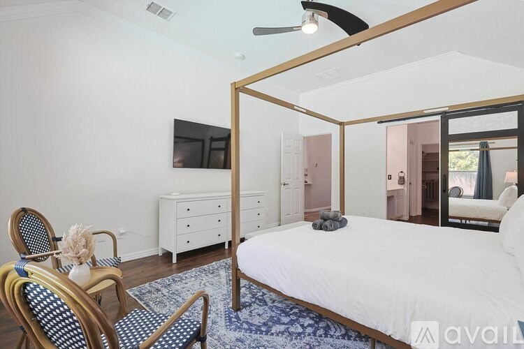 A bedroom with a bed, chair, and a dresser.