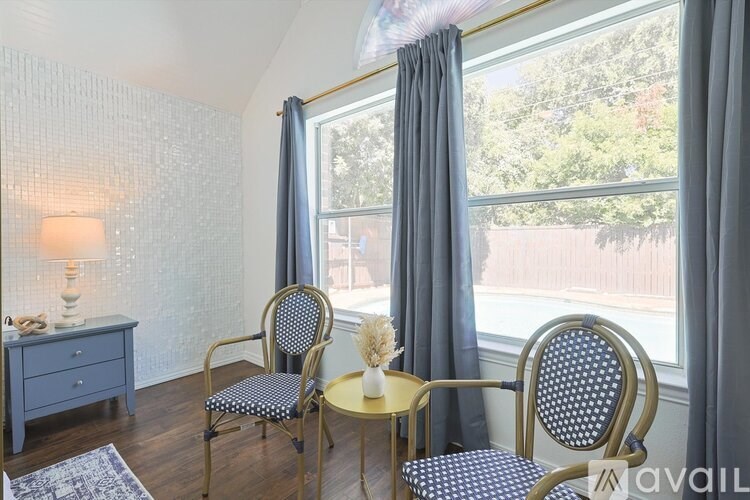 A room with two chairs and a table by a window.