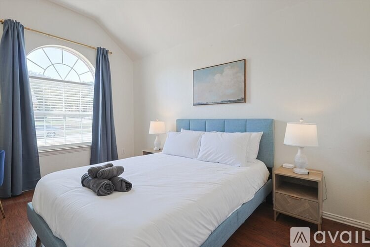 A bedroom with a large bed and a window with curtains.
