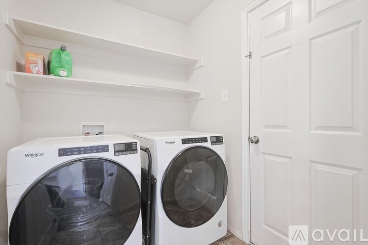 Two white front load washing machines in a laundry room.