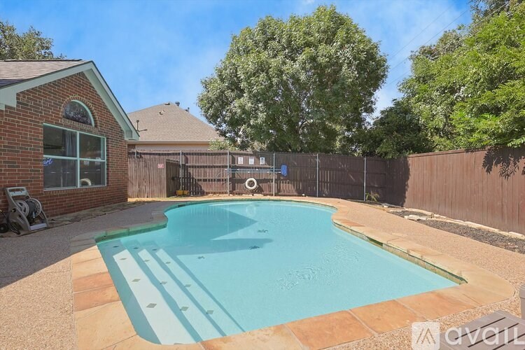 A small residential pool surrounded by a fence and trees.
