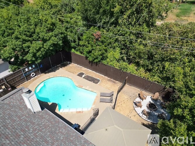 A backyard with a pool and a hot tub surrounded by trees.