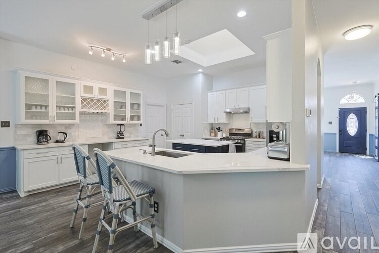 A kitchen with white cabinets and a large island with chairs.