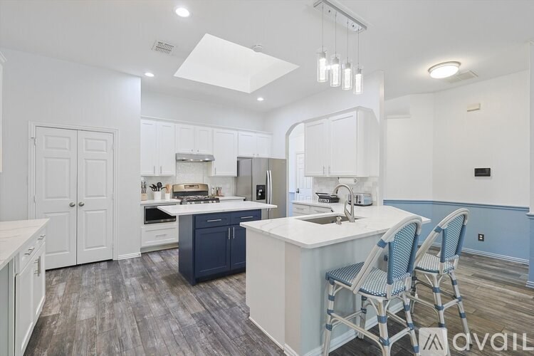 A kitchen with white cabinets and a blue island.