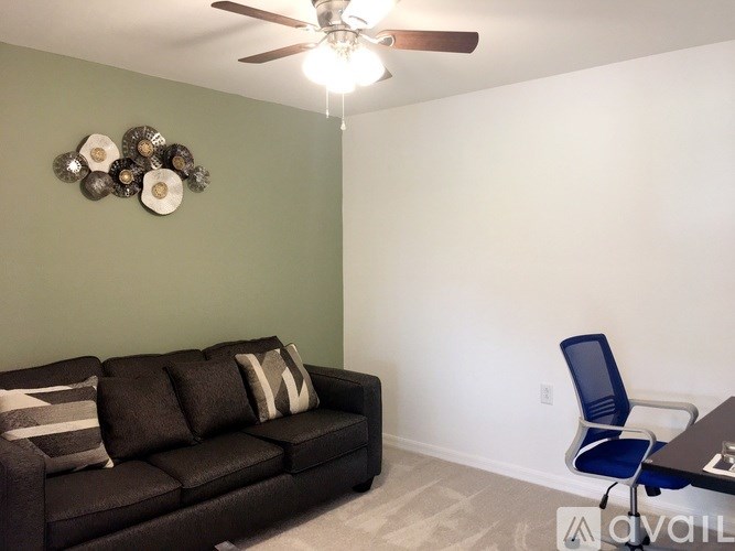 A living room with a black couch and a ceiling fan.