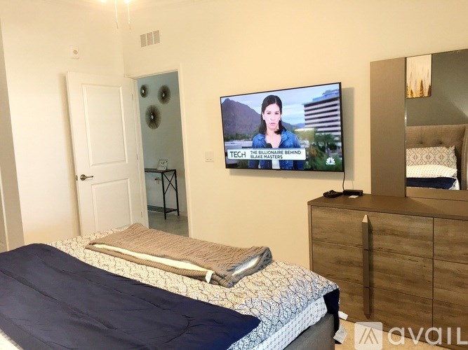 A bedroom with a bed, dresser, and a television displaying a news program.