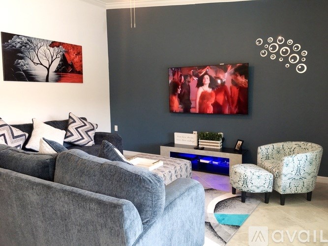 A grey couch with a grey and white pillow is in front of a television.