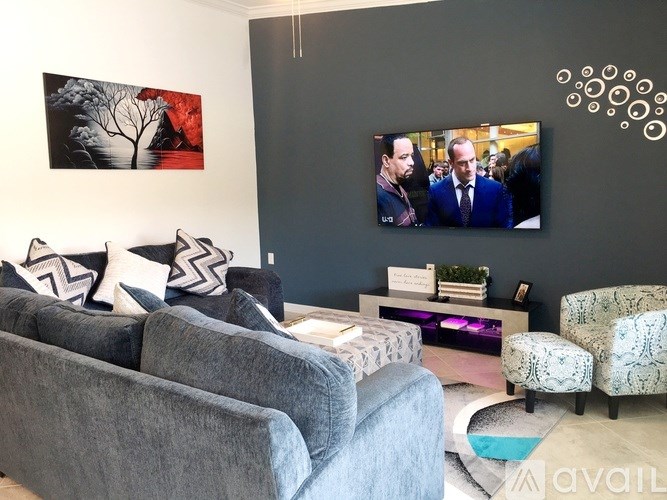 A living room with grey couches and a television playing a show.