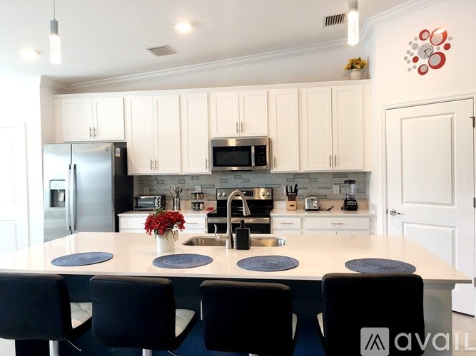 A kitchen with white cabinets and a large island with a sink and a refrigerator.