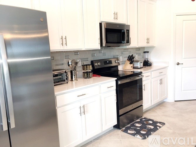 A kitchen with white cabinets and a stainless steel refrigerator.