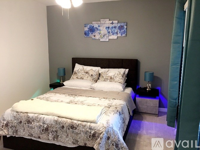 A bedroom with a large bed and a blue and white artwork on the wall.