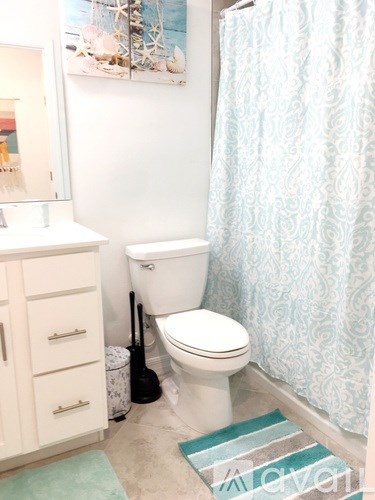A white toilet sits under a shower curtain in a bathroom.