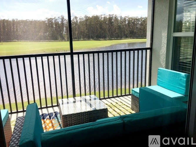 A balcony with a green couch and a table with a view of a golf course.