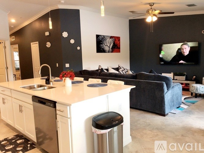 A modern kitchen with a large island and a couch in the background.