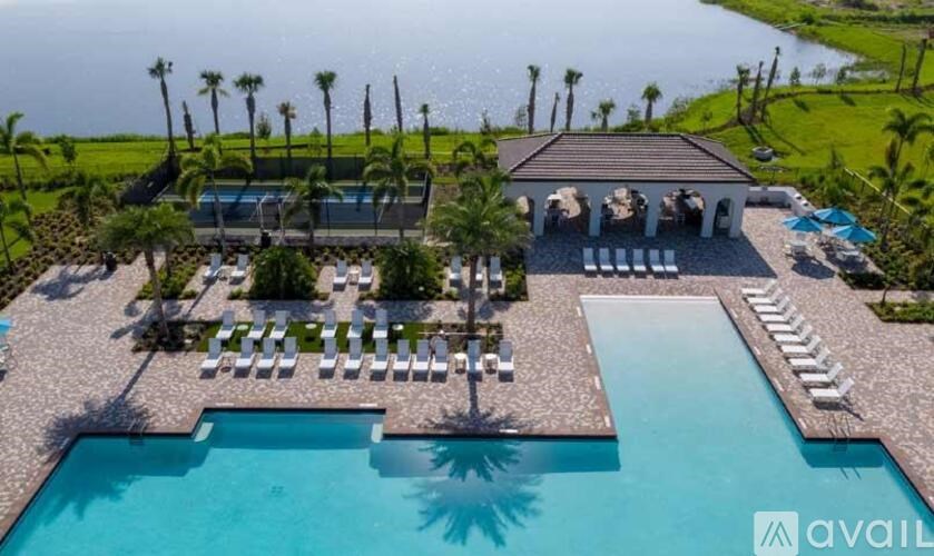 A large swimming pool with sun loungers and a building with a balcony overlooking the pool.