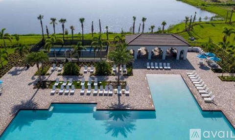A large swimming pool with sun loungers and a building with a balcony overlooking the pool.
