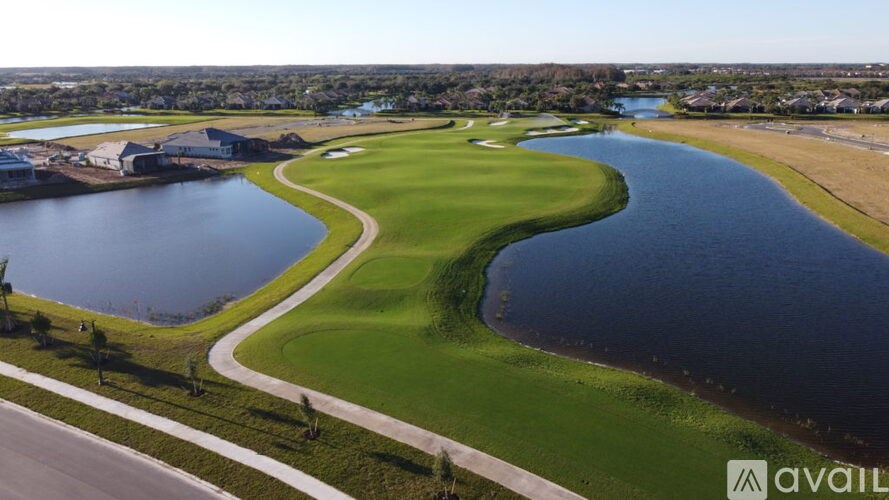 A golf course with a water body and a road.