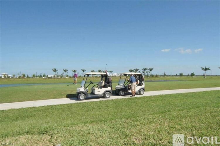 Two golf carts are parked on a grassy area with a clear blue sky in the background.