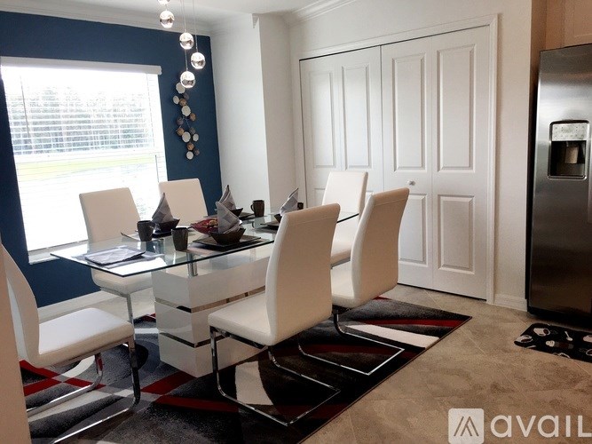 A modern dining room with white chairs and a glass table.