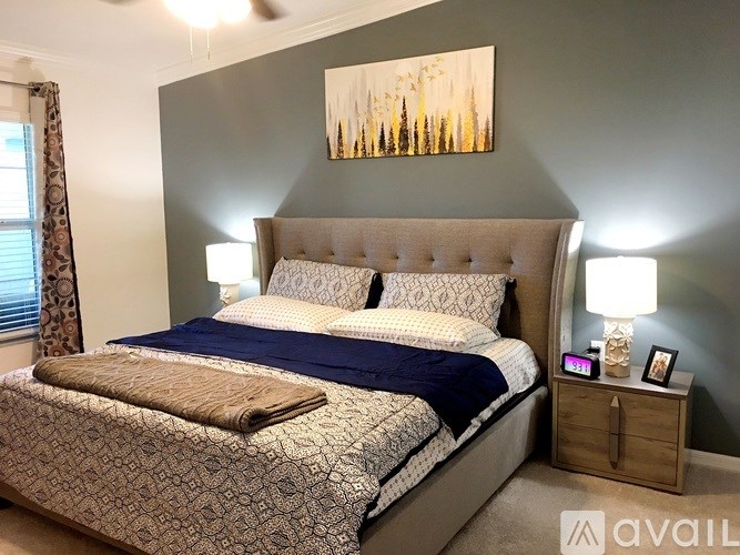 A bedroom with a large bed and a painting on the wall.