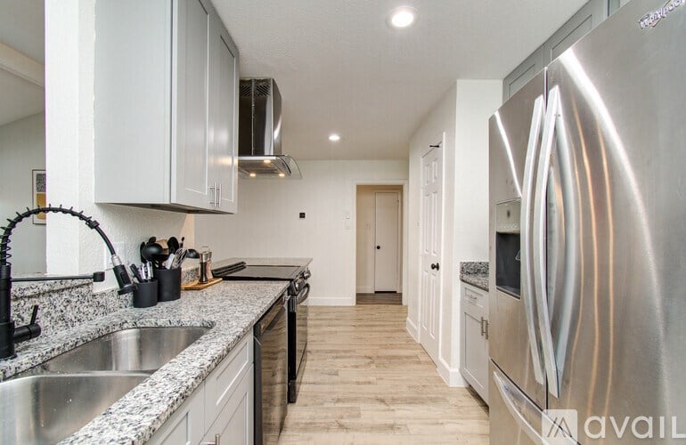 A modern kitchen with a stainless steel refrigerator and a marble countertop.