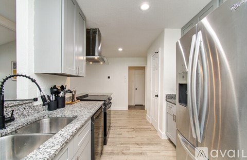 A modern kitchen with a stainless steel refrigerator and a marble countertop.
