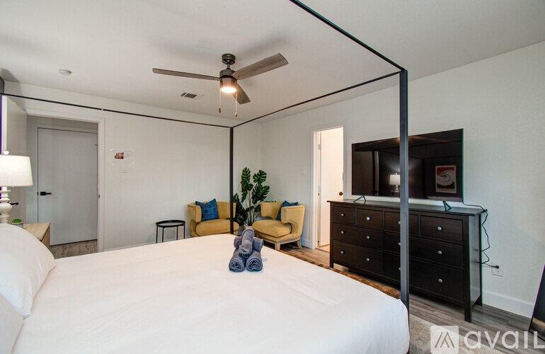 A bedroom with a bed, a ceiling fan, and a dresser.