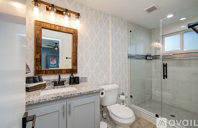 A bathroom with a toilet, sink, mirror, and shower.