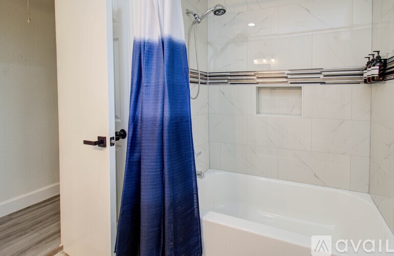 A bathroom with a white tub and a blue shower curtain.