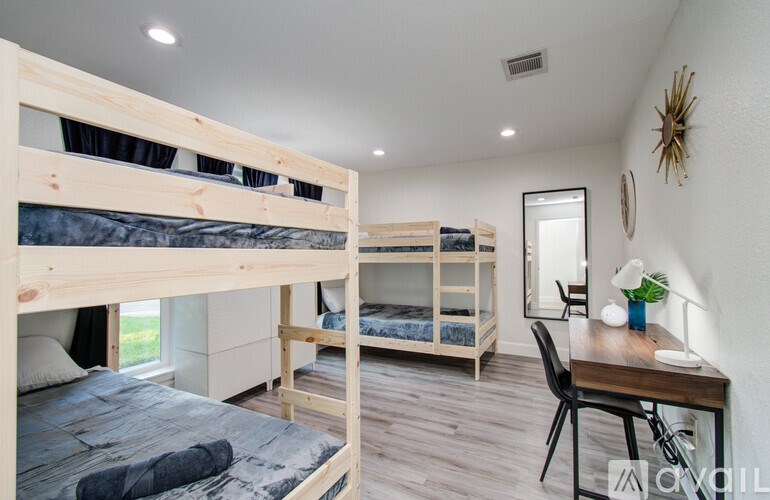A bedroom with two bunk beds and a desk.