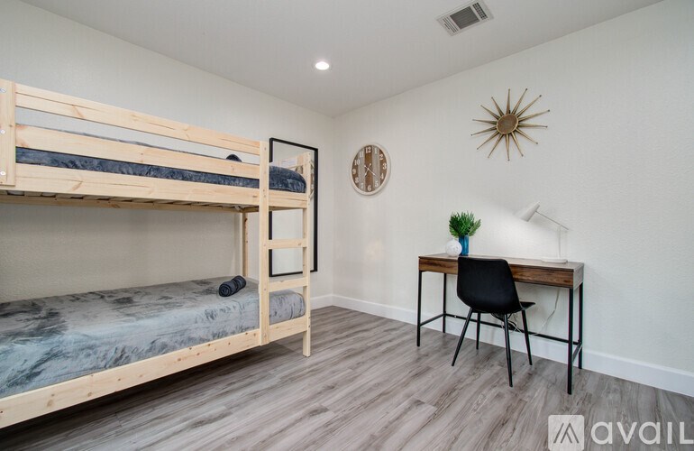 A room with a bunk bed, a desk, and a chair.