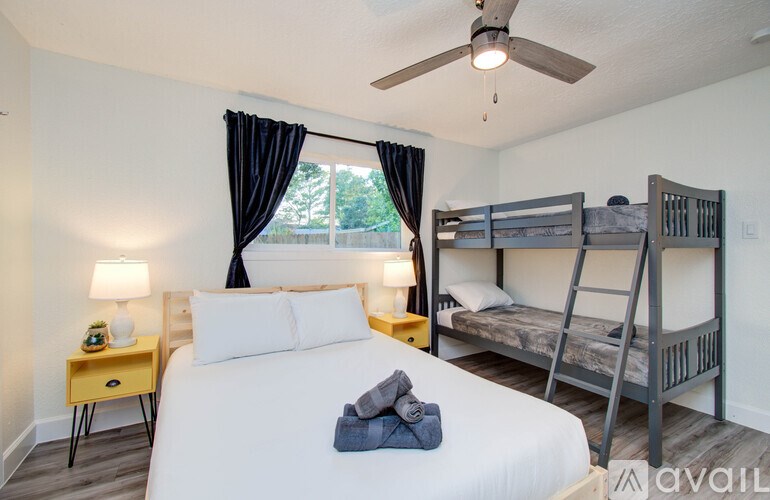 A bedroom with a white bed, a yellow nightstand, and a bunk bed.