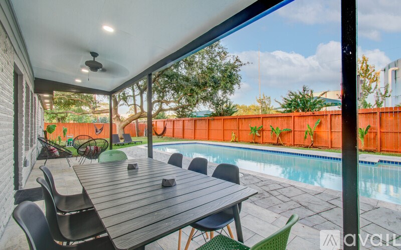 A patio with a table and chairs overlooking a pool.