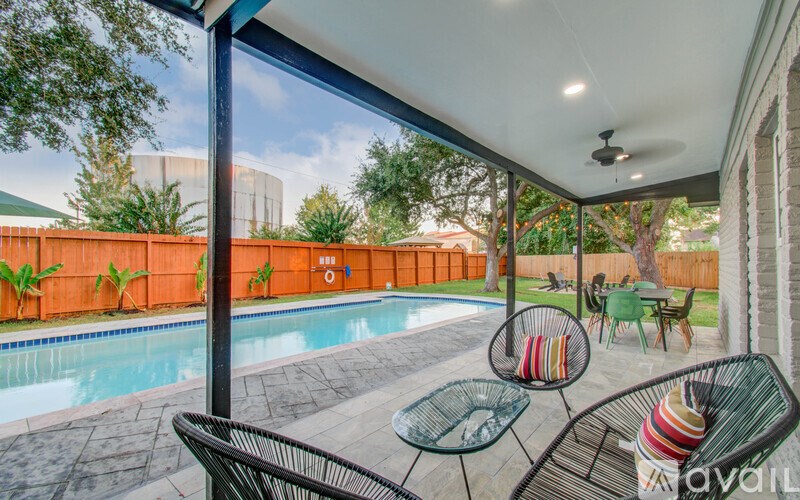 A patio with a table and chairs overlooking a pool.
