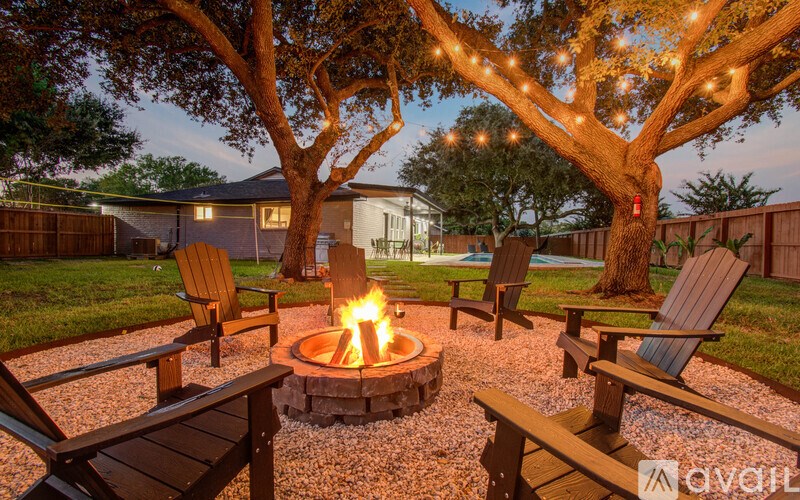 A fire pit in the middle of a gravel area with chairs around it.