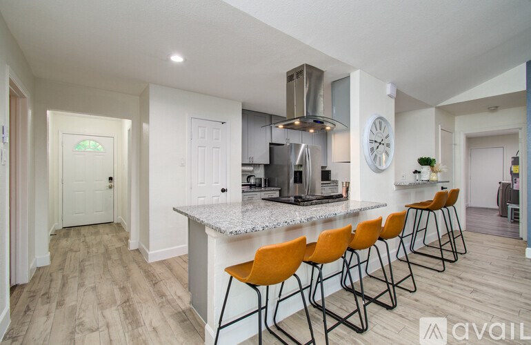A kitchen with a bar area and orange chairs.