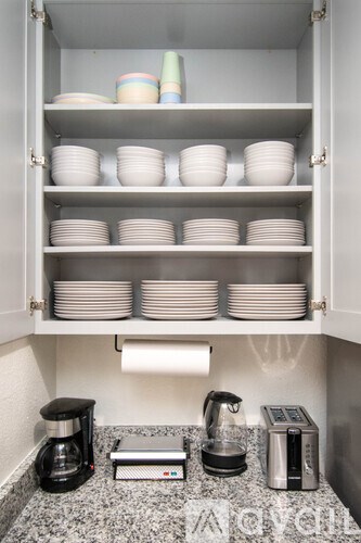 A kitchen cabinet with plates and a coffee maker.
