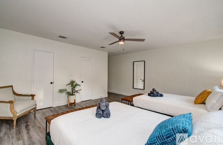 A bedroom with a bed, chair, and plant.