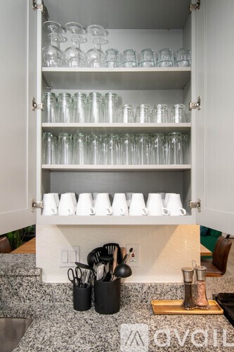 A kitchen counter with a set of glasses on the shelf.